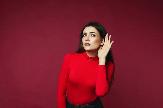 Brunette woman is trying to hear something standing