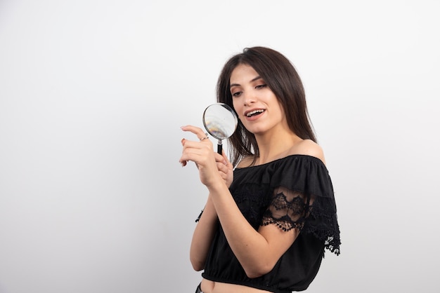 Brunette woman looking at her hand with magnifying glass.