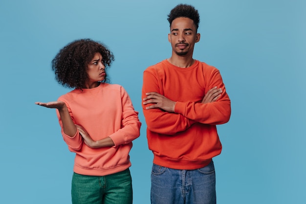 Free photo brunette woman and man quarrel on blue wall