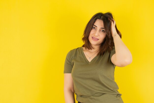 Brunette woman model standing and posing against yellow wall 