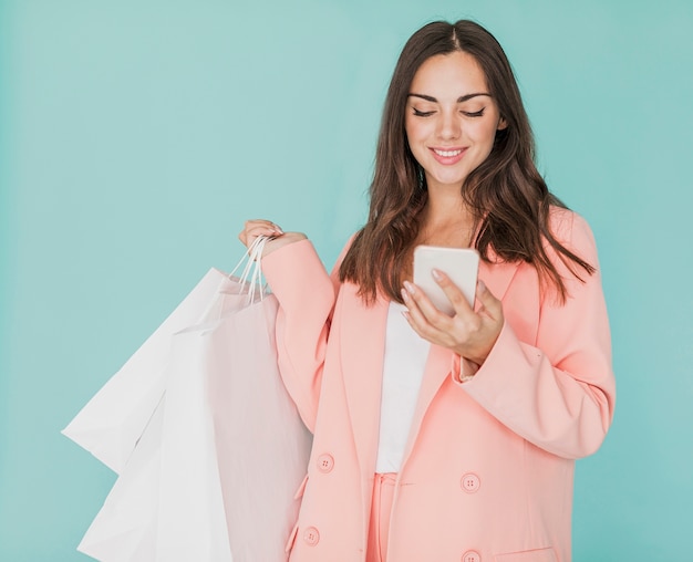 Brunette woman  in pink jacket looking at smartphone