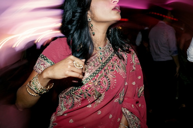 Free photo brunette woman in pink saree stands in the crowd of people