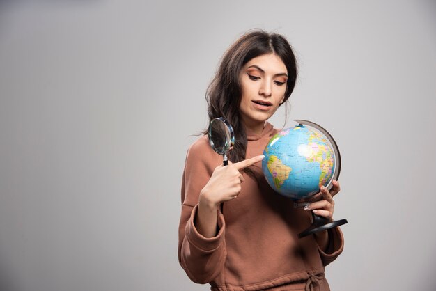 Brunette woman pointing at small place on globe