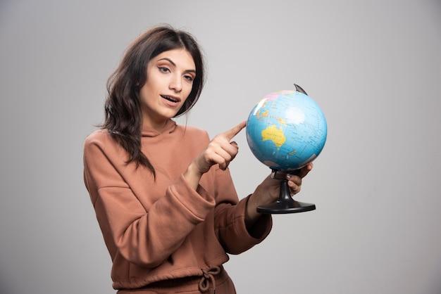 Brunette woman pointing at small place on globe