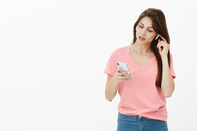 брюнетка женщина позирует в студии со своим телефоном и наушниками