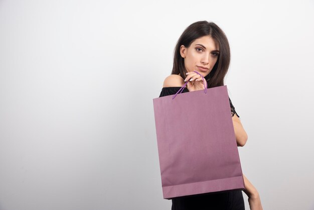 Brunette woman posing with shopping bag.