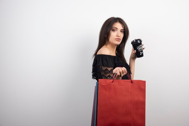 Brunette woman posing with shopping bags and coffee cup.