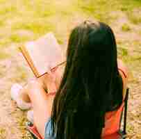 무료 사진 자연 속에서 갈색 머리 여자 읽기 책