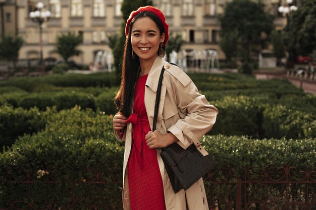 Brunette woman in red beret and bright dress smiles outside