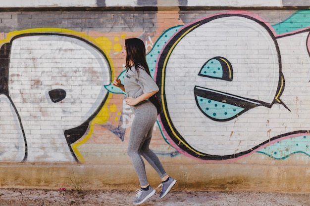 Brunette woman running against concrete wall