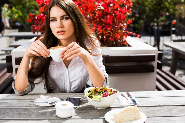 Brunette woman sits at the table with coffee