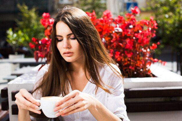 ブルネットの女性はコーヒーでテーブルに座って