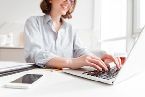 brunette woman typing email on laptop computer while sitting at home, selective focus on hand