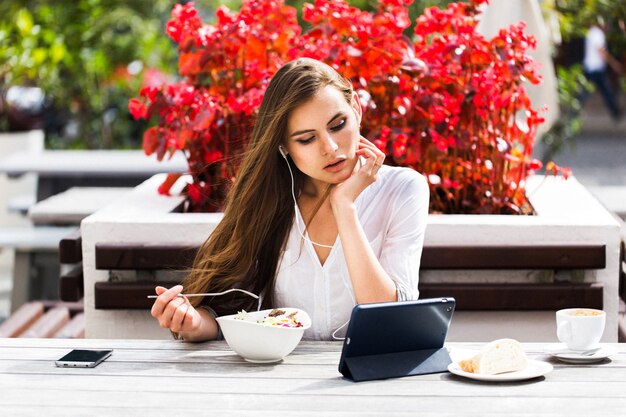 Brunette woman watches something on her tablet while sitting in the restaurant