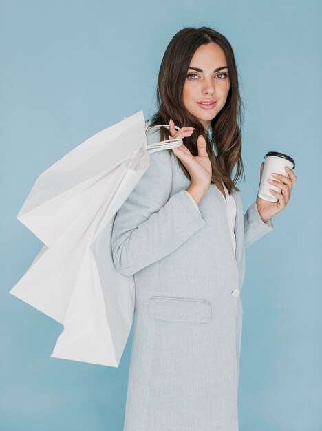 Brunette woman with coffee and shopping bags on shoulder