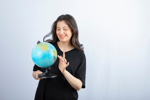 Brunette woman with long hair chooses a place to travel on the globe . 