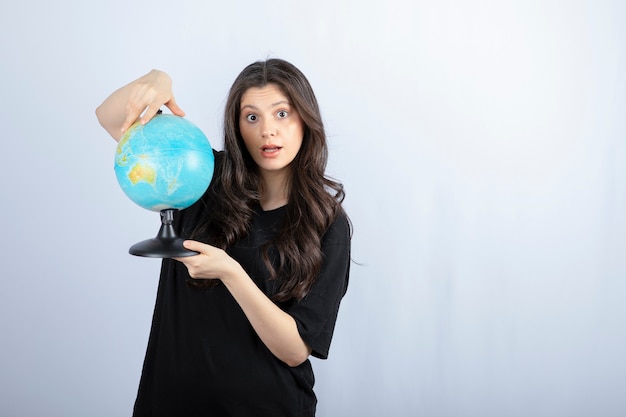 Brunette woman with long hair holding world globe and posing .