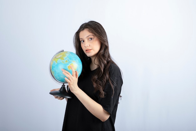 Brunette woman with long hair holding world globe and posing . 