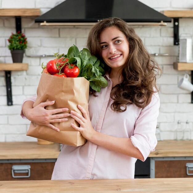 Donna bruna con un sacchetto di carta pieno di cibo sano