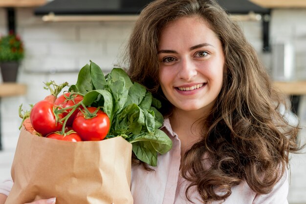 Brunette woman with a paper bag full of healthy food