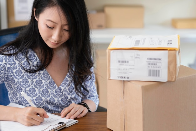 Free photo brunette woman writing next to parcels