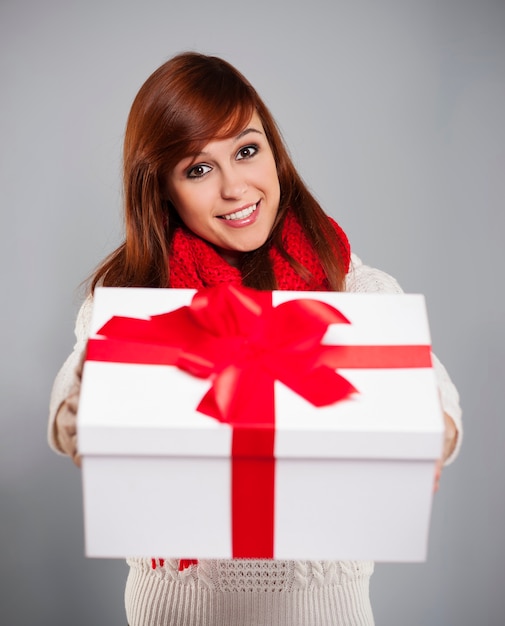 Brunette young woman giving white christmas gift with red ribbon