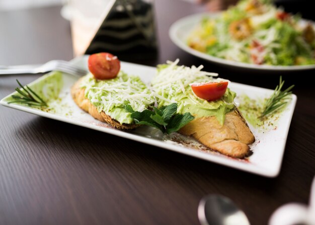 Bruschetta bread with pesto sauce; grated cheese and cherry tomato on plate