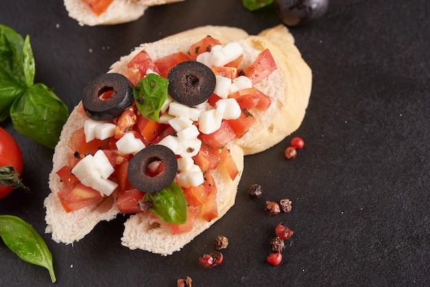 Bruschetta with tomatoes, mozzarella cheese and basil on a cutting board. Traditional italian appetizer or snack, antipasto. Caprese salad bruschetta. Top view with copy space. Flat lay.