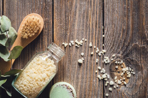 Brush sea salt soap and dried flowers on wooden background