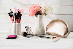 Free photo brushes and cosmetics near flowers and bag