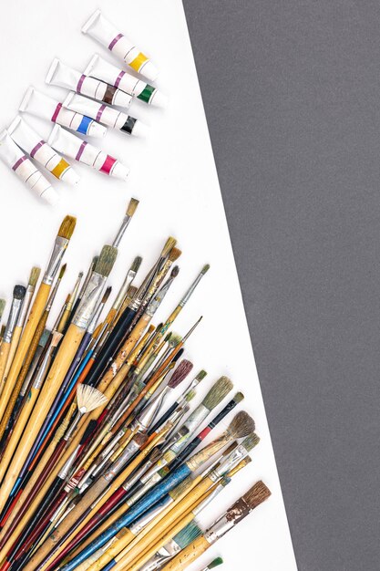 Brushes for drawing and paint on paper colored background flat lay