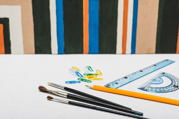 Brushes and stationery near abstract painting