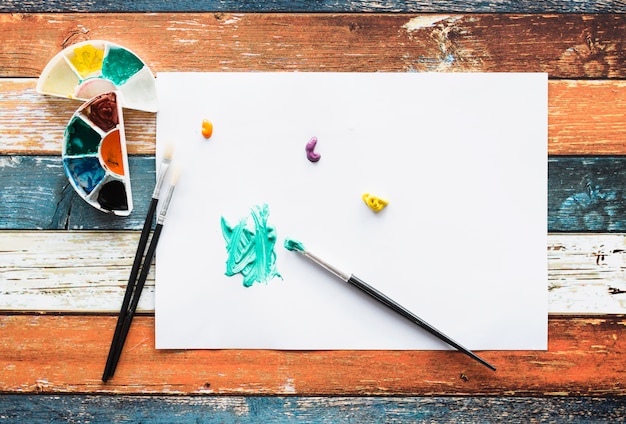 Brushstroke and paint stain on white page over wooden desk