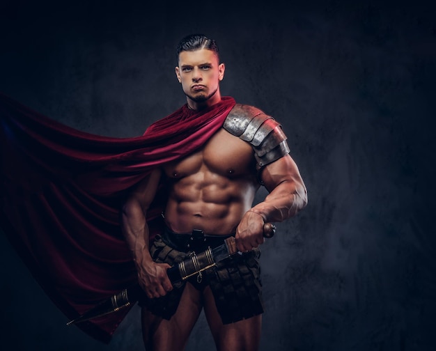 Бесплатное фото Жестокий древнегреческий воин с мускулистым телом в боевой форме позирует на темном фоне.