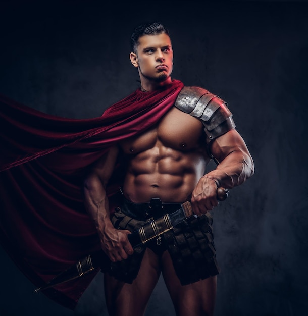 Brutal ancient Greece warrior with a muscular body in battle uniforms posing on a dark background.