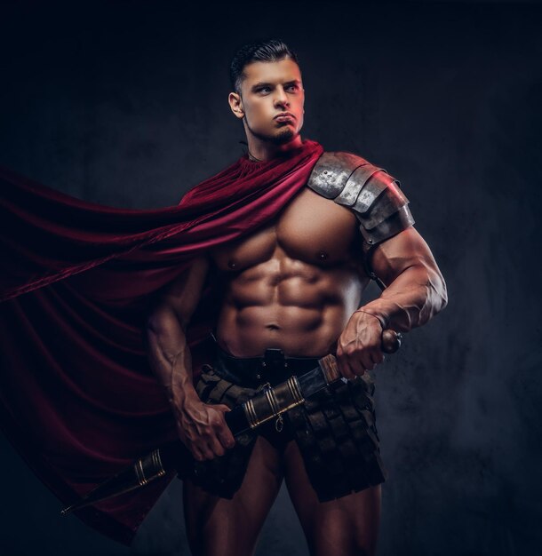 Brutal ancient Greece warrior with a muscular body in battle uniforms posing on a dark background.