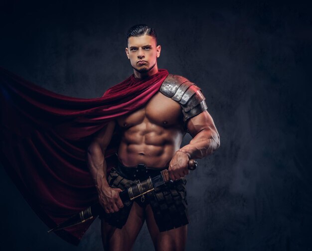 brutal ancient greece warrior with a muscular body in battle uniforms posing on a dark background.