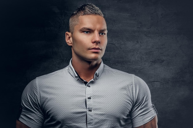 Free photo brutal athletic male vogue model dressed in a white shirt on grey background.
