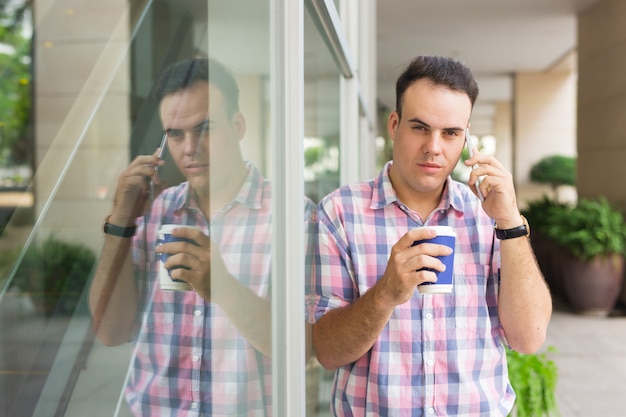 屋外でコーヒーを飲むチェッカードレスで残忍なハンサムな男