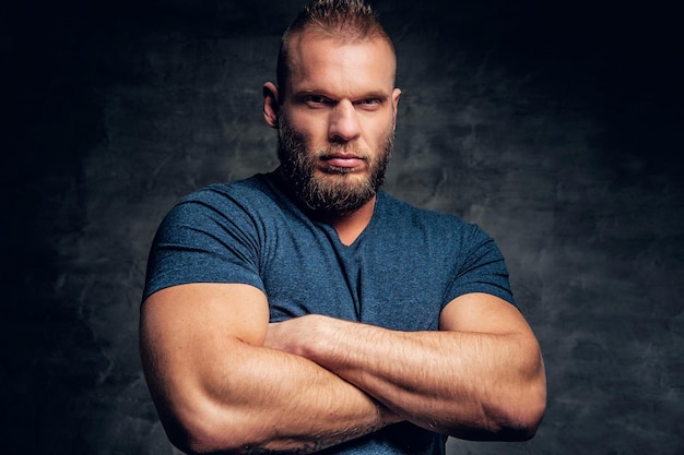 Free photo brutal muscular male with crossed arms, dressed in a blue t shirt over grey background.