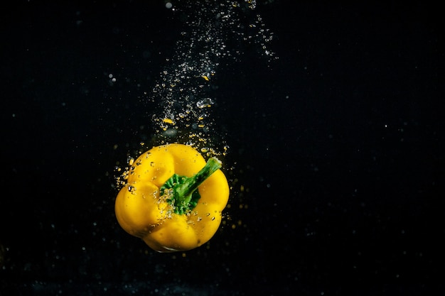 Bubbles raise around yellow pepper falling in water