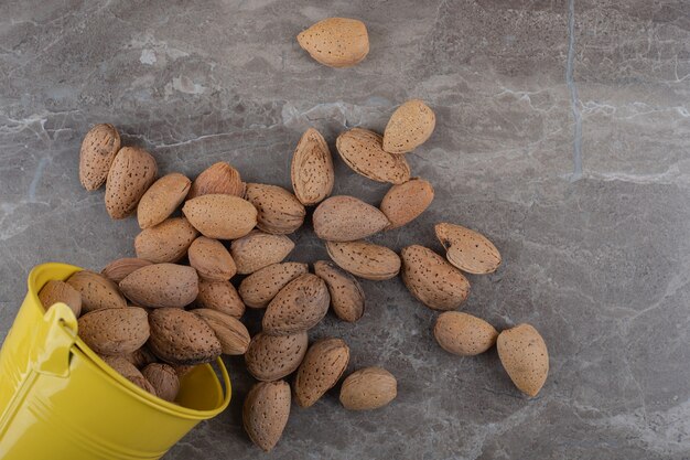 Bucket and almonds on the marble surface