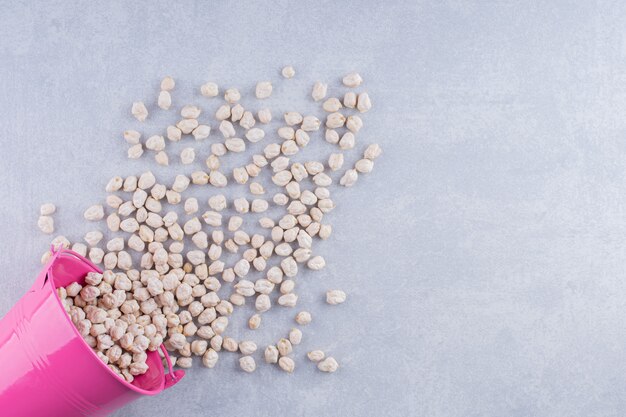 Bucket of chickpeas spilled over on marble surface