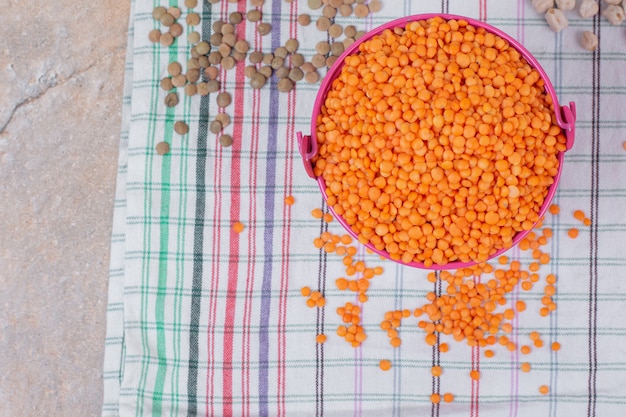 Free photo bucket of dried red lentils on tablecloth.