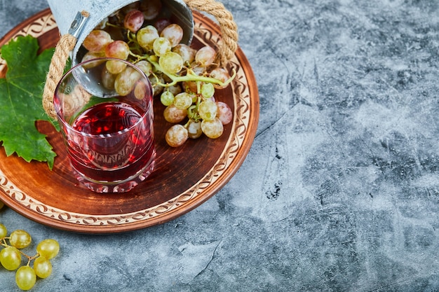 Ведро винограда и стакан сока на мраморе.