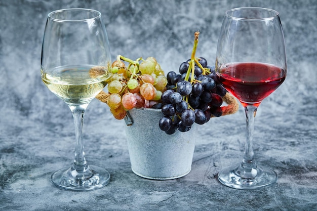 Bucket of grapes and glasses of wone on marble.