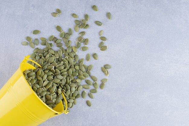 Bucket of pepitas fallen over and scattered on marble surface