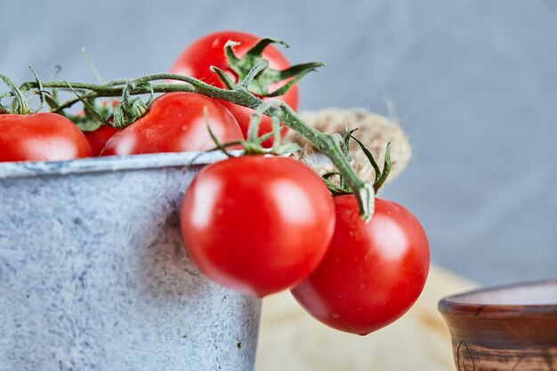 Bucket of red juicy tomatoes on wooden table.