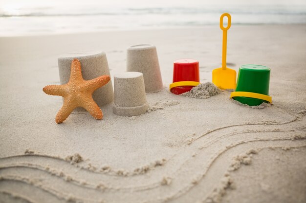 Bucket, spade, starfish and sand castles on beach