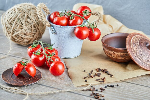 Bucket of tomatoes and half cut tomato on wooden table